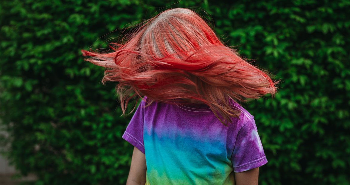 Criança com cabelo vermelho cereja vibrante brincando ao ar livre